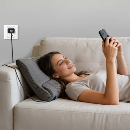Dark grey neck massager pillow with remote controller in hand for home use