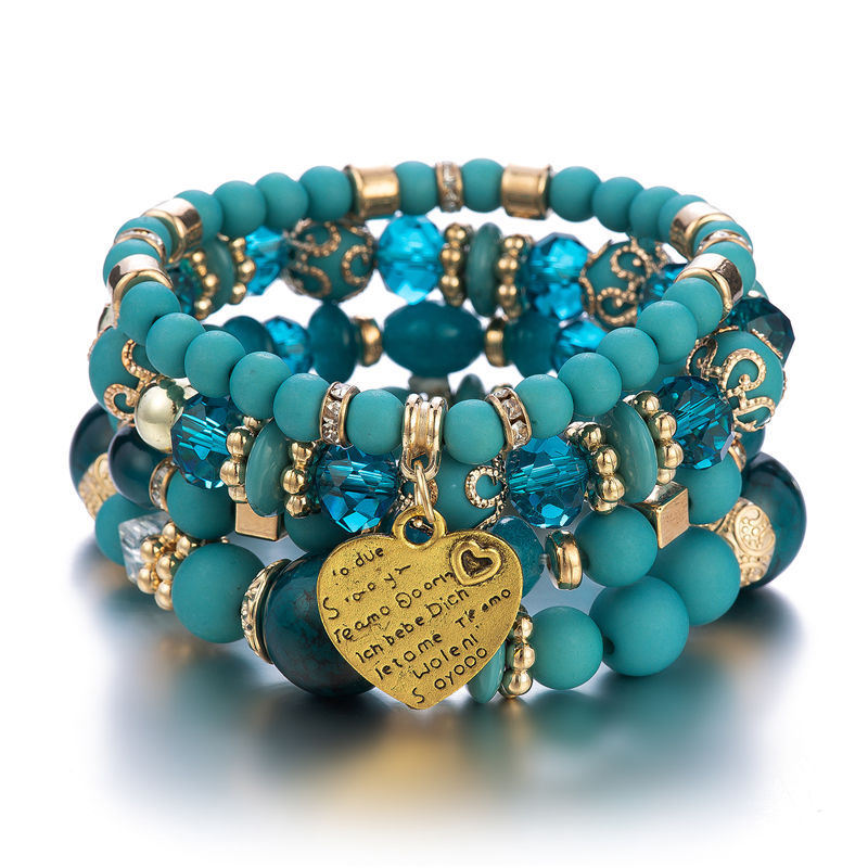 Layered charm bracelet set with teal bead strands and blue heart charm centerpiece