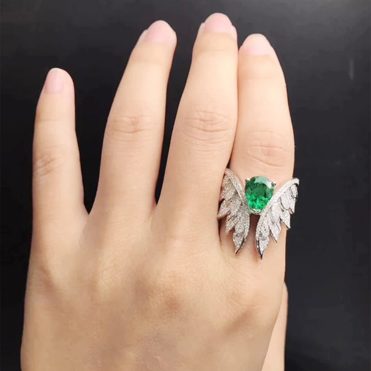 Green and silver wing zircon cluster ring on open palm