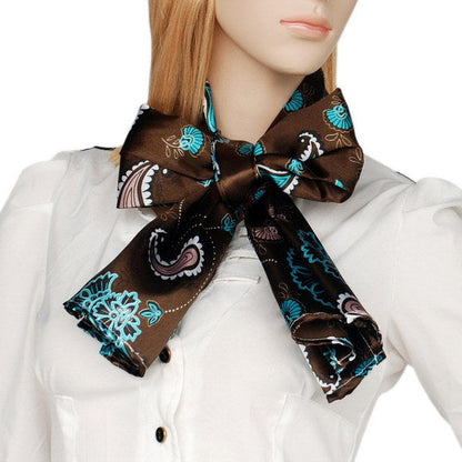 Brown silk scarf with teal paisley floral print, tied bow at collar
