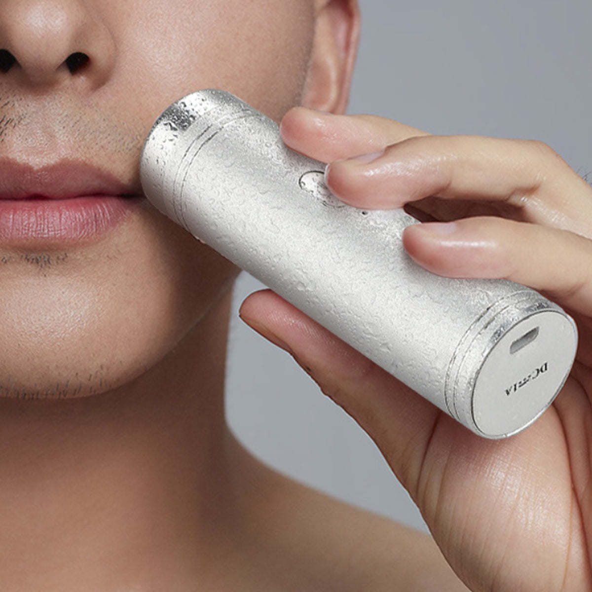 Silver mini USB shaver close-up at the face, with foil head pressed to skin