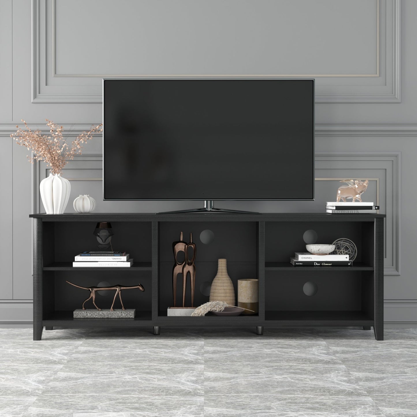Black TV stand with open cubbies and three drawers with round pulls, holding a TV.
