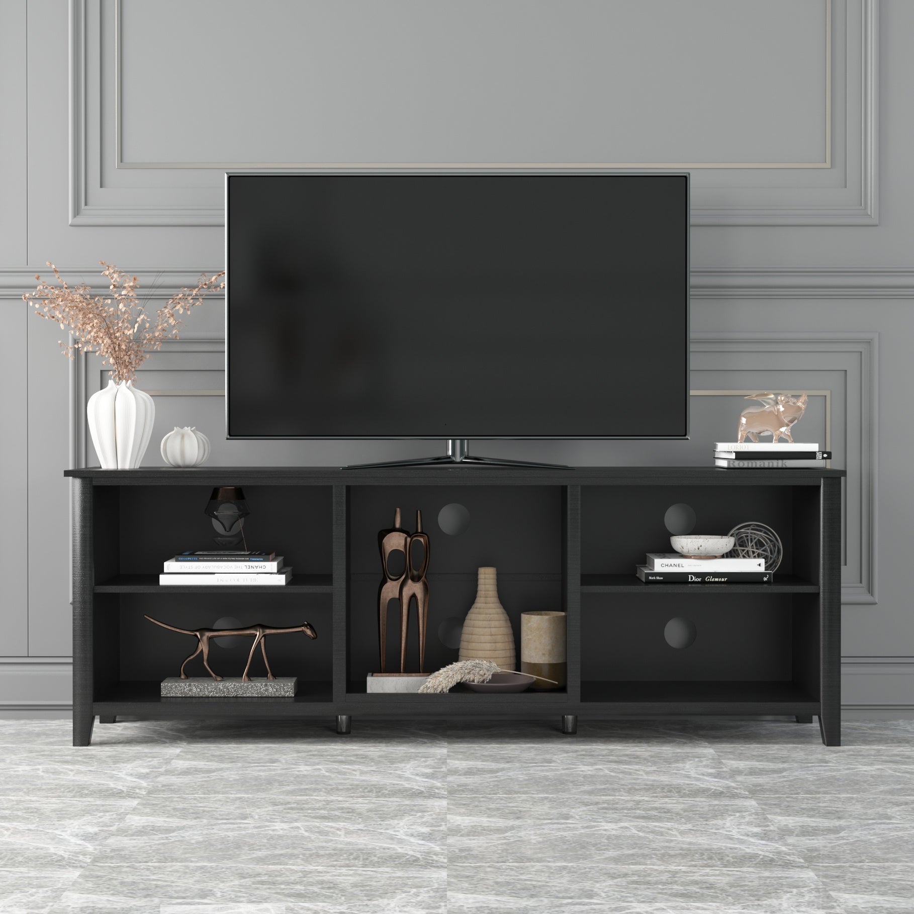 Black TV stand with open cubbies and three drawers with round pulls, holding a TV.