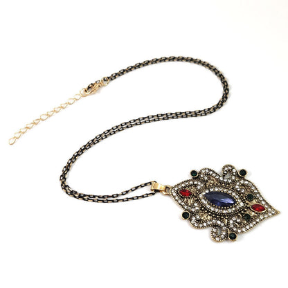 Gold-tone necklace chain with ornate blue pendant and small red accents