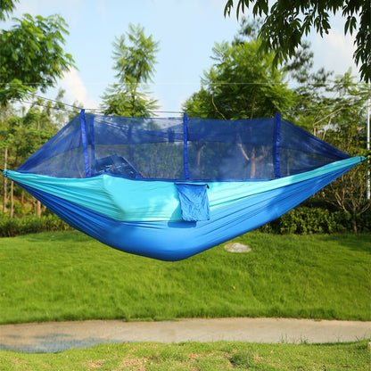 Blue two-person hammock with mosquito net spread outdoors