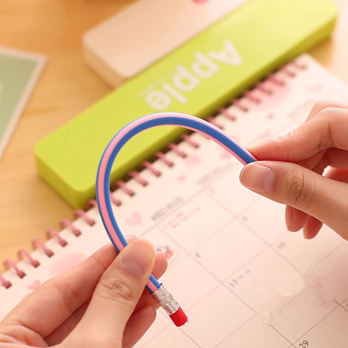 Flexible striped soft pencil with red eraser held in hand