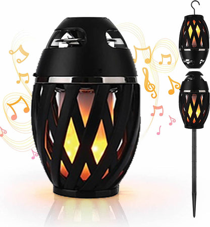 Outdoor LED torch speaker, black flame lantern with glowing amber window pattern, on stake.
