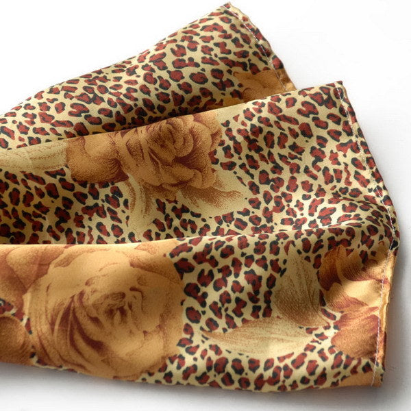 Gold silk scarf close-up with leopard print and large rose motifs, folded edge