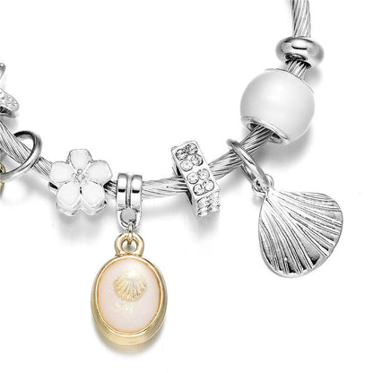 Silver wrap bangle bracelet detail with white flower, oval shell pendant and fan charm