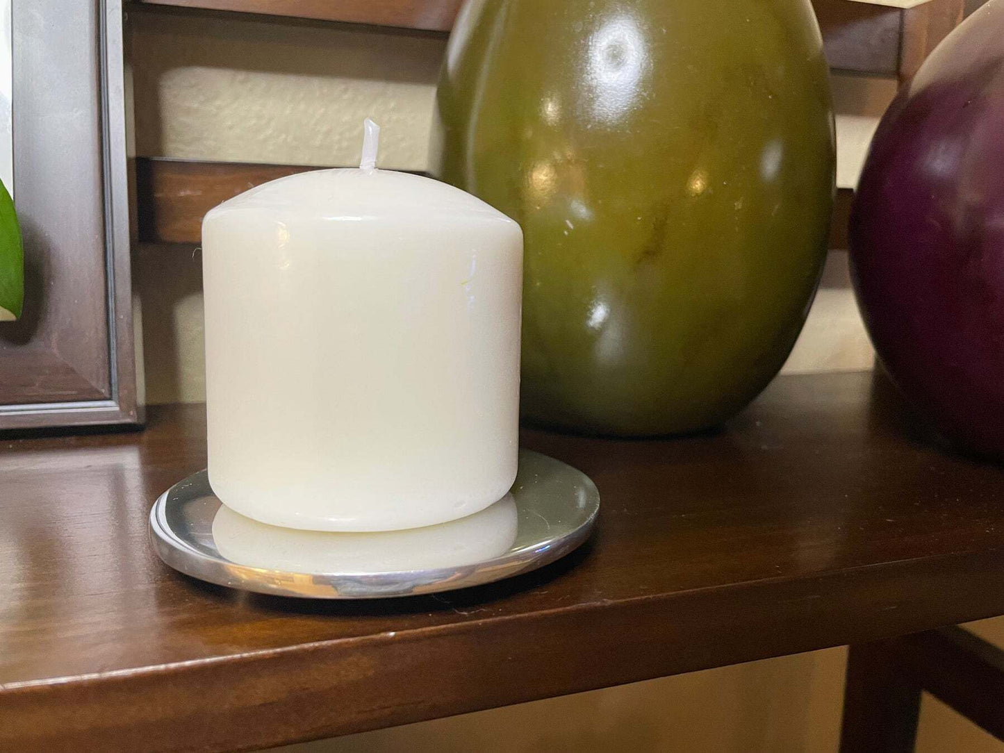 White pillar candle on round metal candle holder/coaster