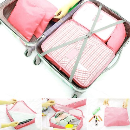 Pink packing cubes strapped inside a suitcase with green elastic bands
