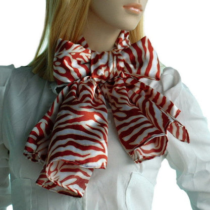 Red and white zebra-print silk scarf with tied bow and soft drape.
