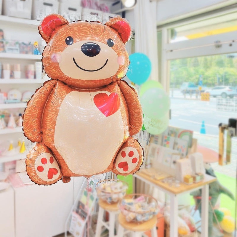 Brown bear foil balloon with red heart on white belly; paw pads visible
