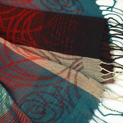 Pashmina shawl fabric close-up with woven pattern and fringe tassels in teal and red