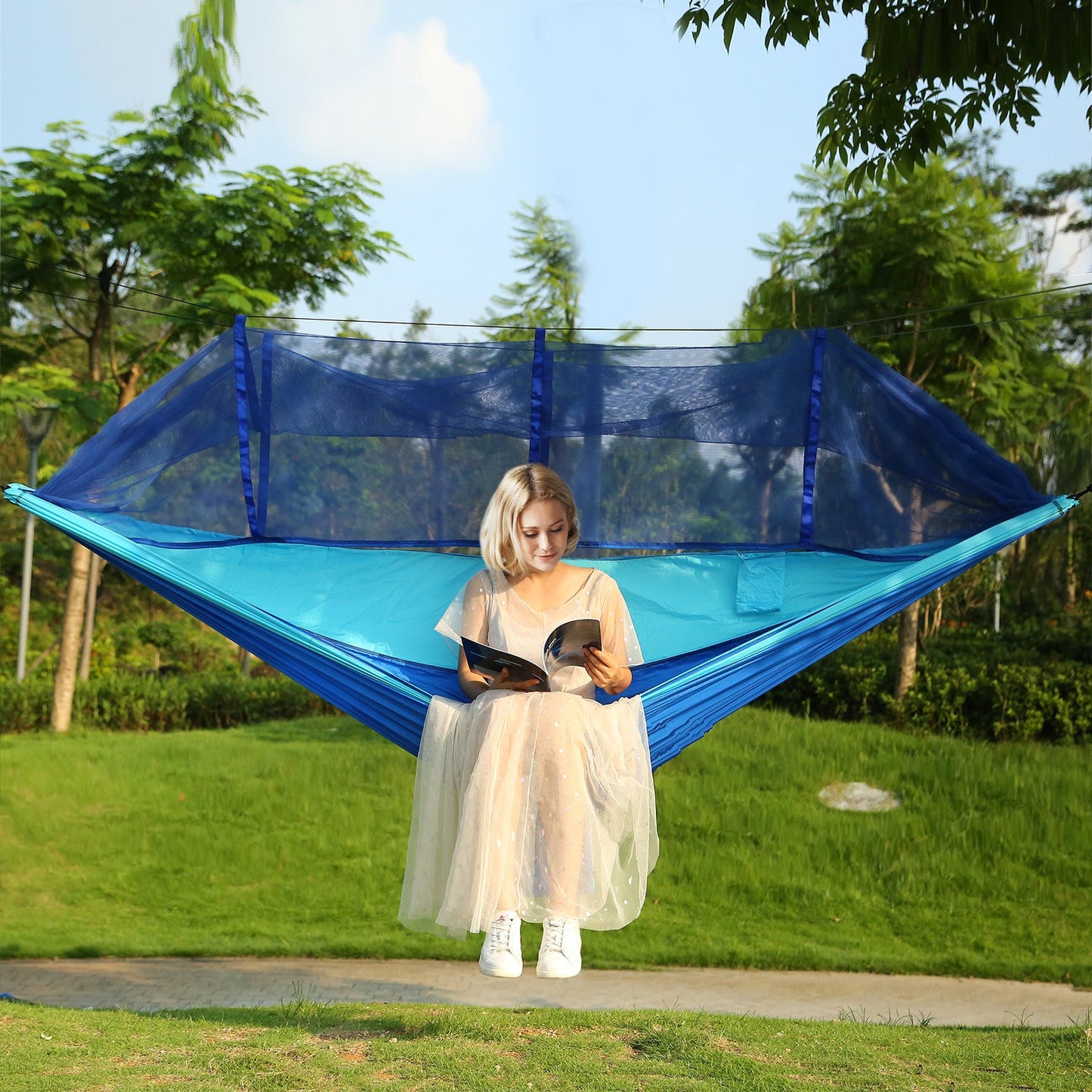 Two-person hammock with mosquito net, blue and teal fabric, with person nearby