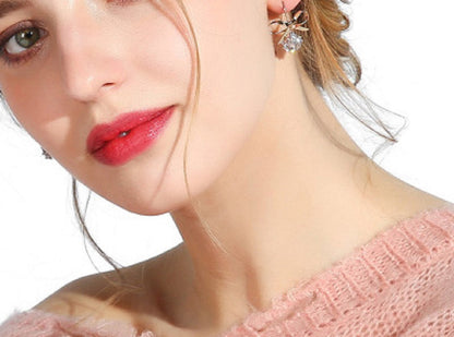 Gold-tone bow earrings with a round zircon stone, worn on the ear