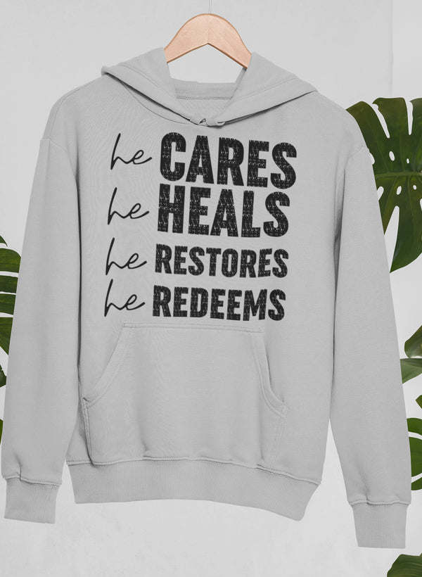 Light gray hoodie with pocket and 'he CARES he HEALS he RESTORES he REDEEMS'