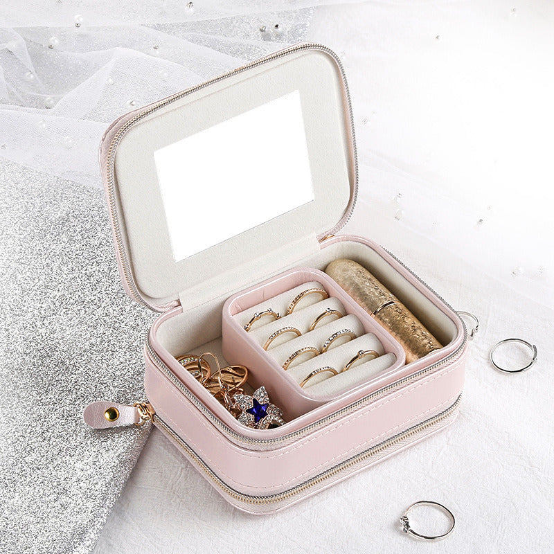 Pink jewelry organizer case with open lid, mirror panel, and ring compartments