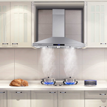 Stainless steel wall range hood above a stovetop with visible backsplash tiles