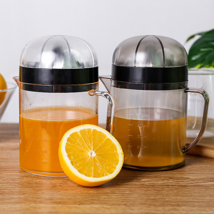 Clear citrus juicer pitcher with black lid, handle spout, and lemon half