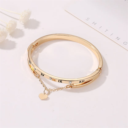 Gold stainless steel bangle bracelet with Roman numeral inlays, small stones, heart charm