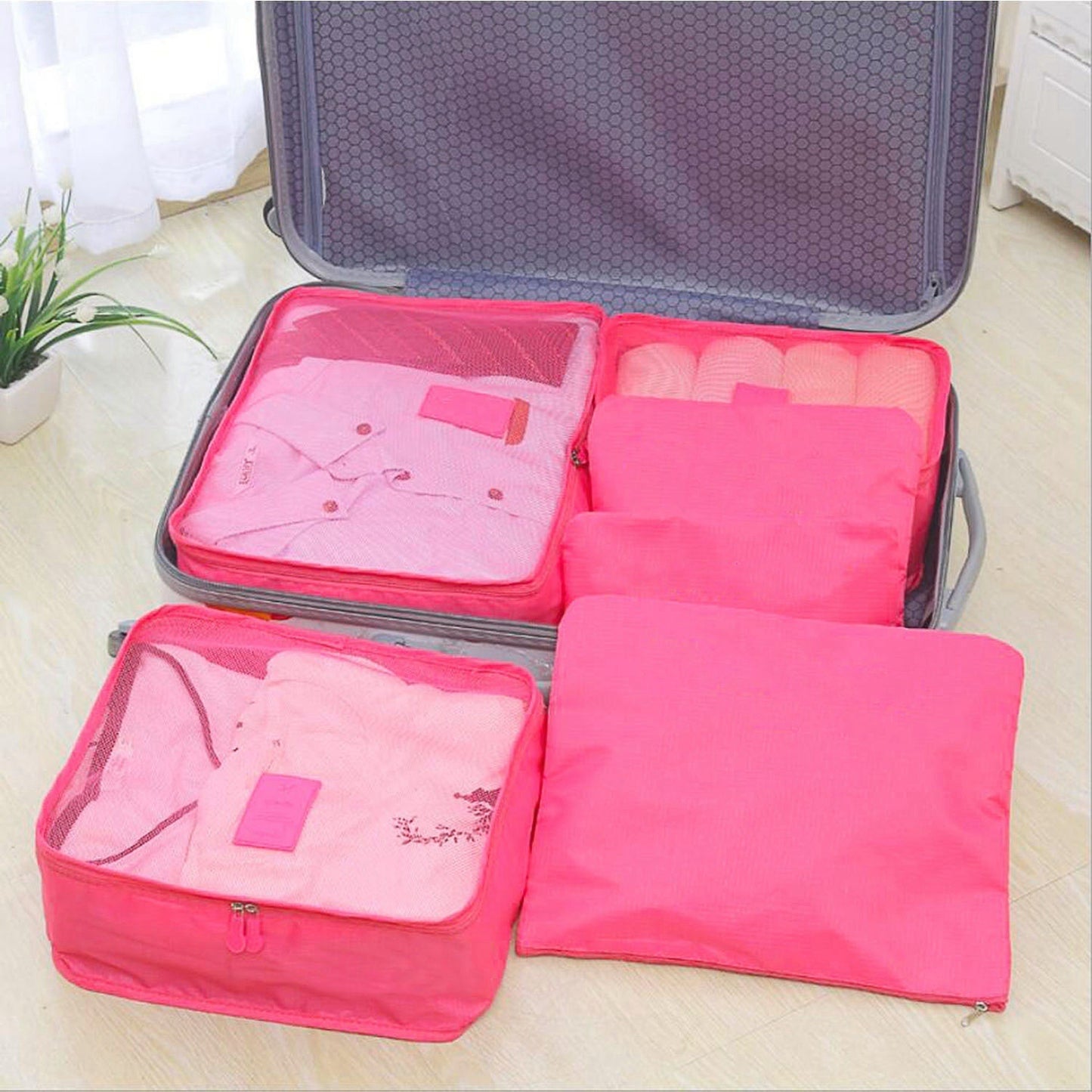 Pink packing cubes set with mesh top panels inside a gray travel case