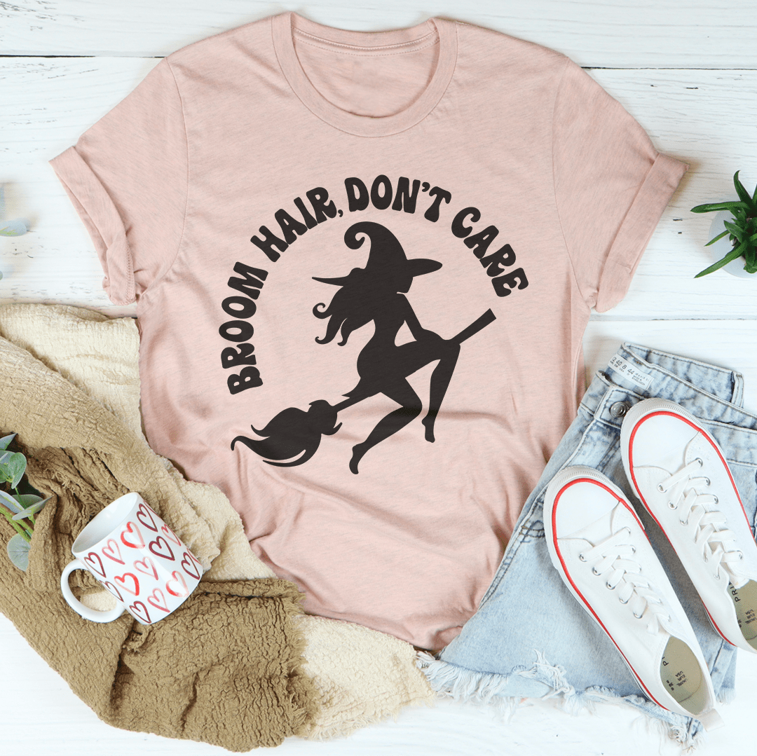 Broom Hair Don't Care T-shirt in blush pink with broom-holding silhouette graphic.
