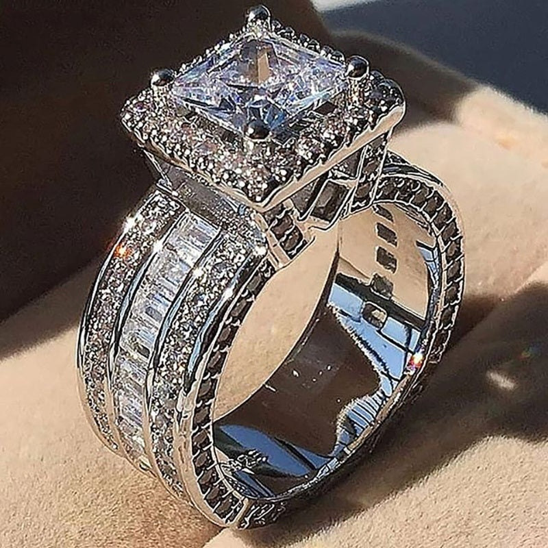 Square-cut zircon halo engagement ring with silver-toned prong setting and ornate band