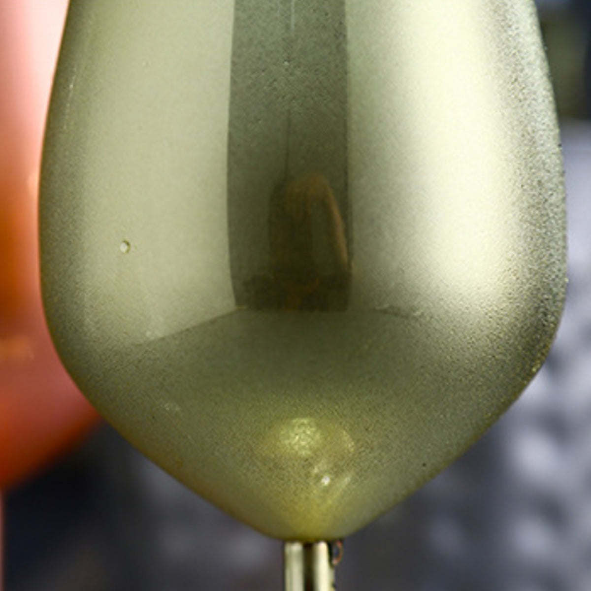 Close-up of a metallic gold-green stemmed cocktail glass bowl with condensation