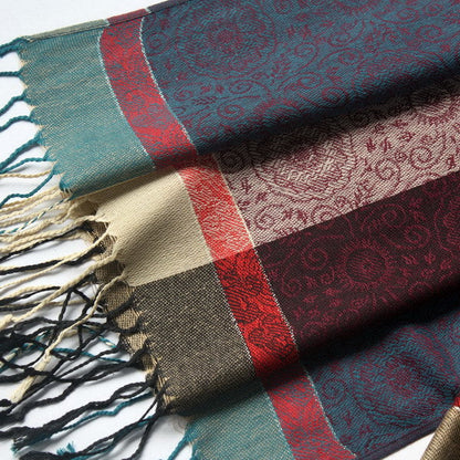 Close-up pashmina fabric with teal and burgundy border, decorative weave, tassel fringe
