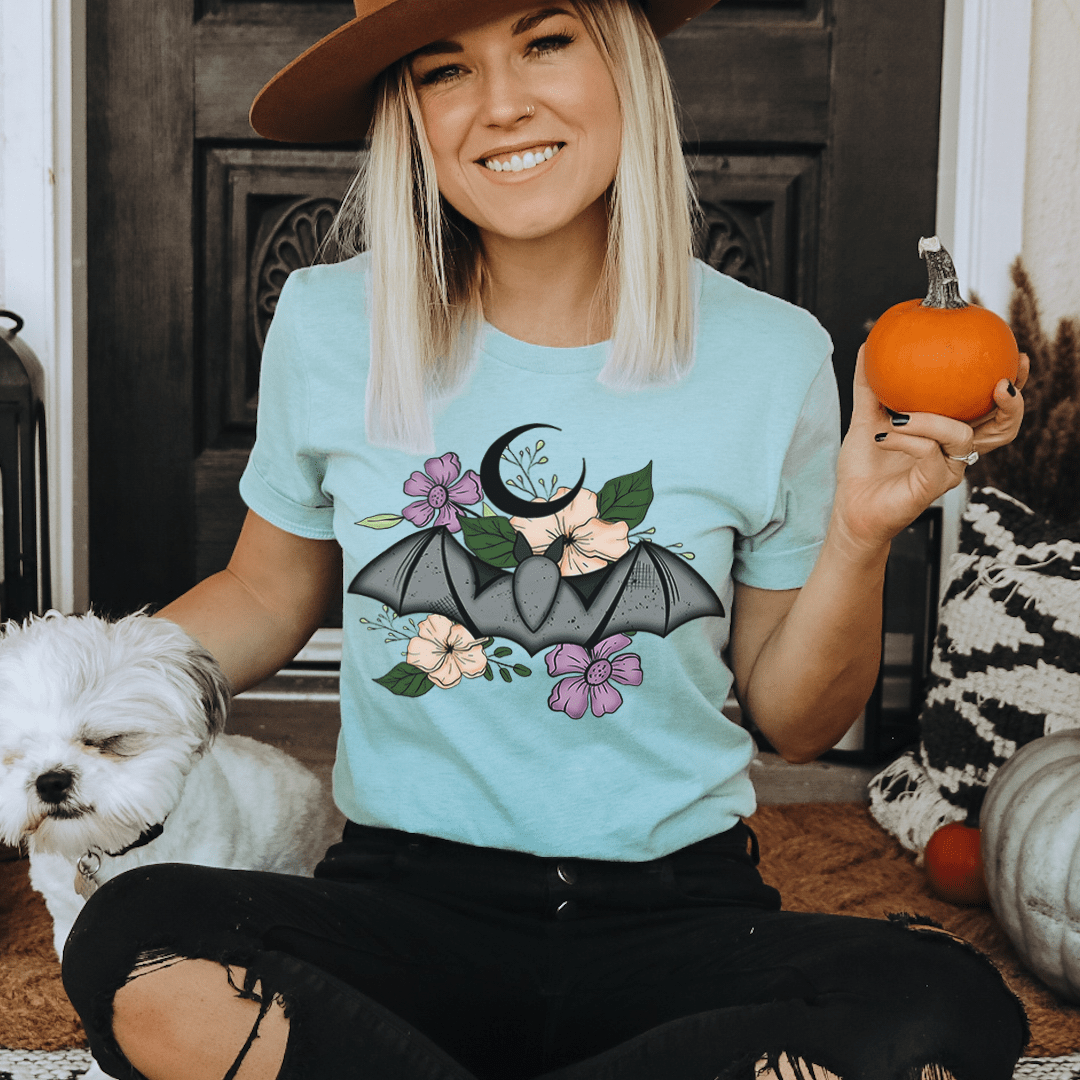 Light blue floral bat T-shirt with illustrated bat and flowers on the front