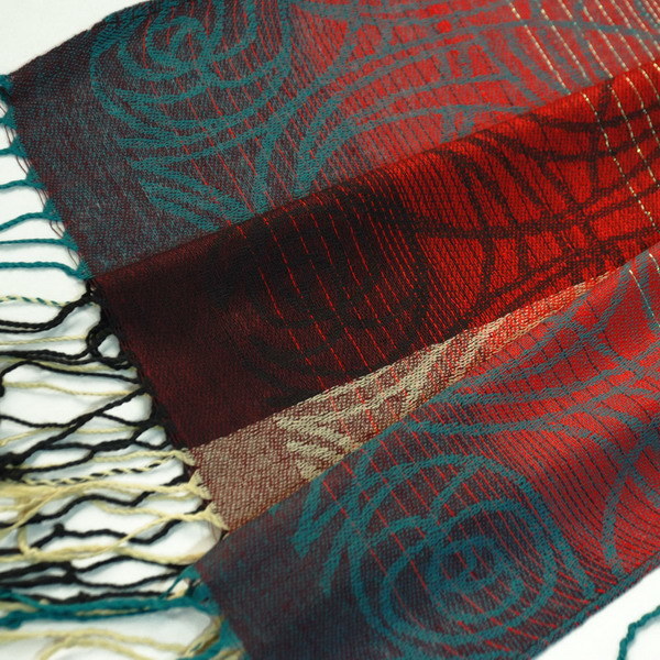 Pashmina shawl edge close-up with woven motifs and long fringe tassels in red, teal, beige