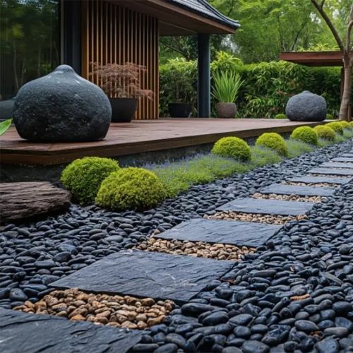 Polished black river rock landscaping bed with smooth stones and flat edging pieces