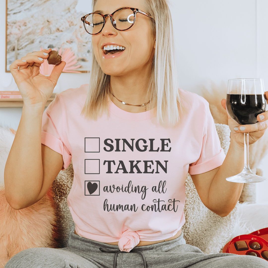 Pink T-shirt worn by model with 'SINGLE TAKEN' and 'avoiding all human contact' graphic
