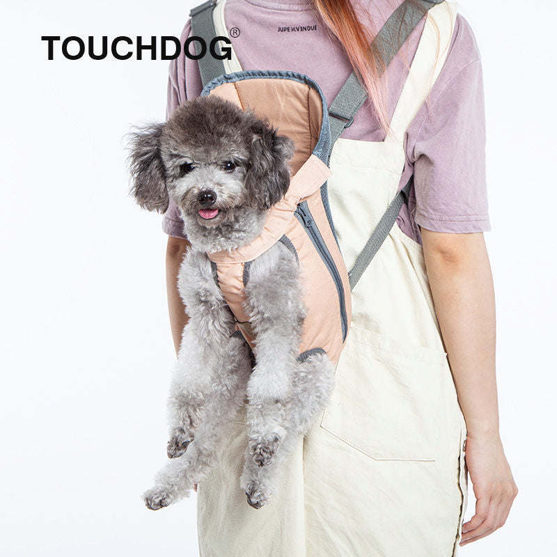 Dog wearing beige and teal front/backpack carrier on person with paw openings