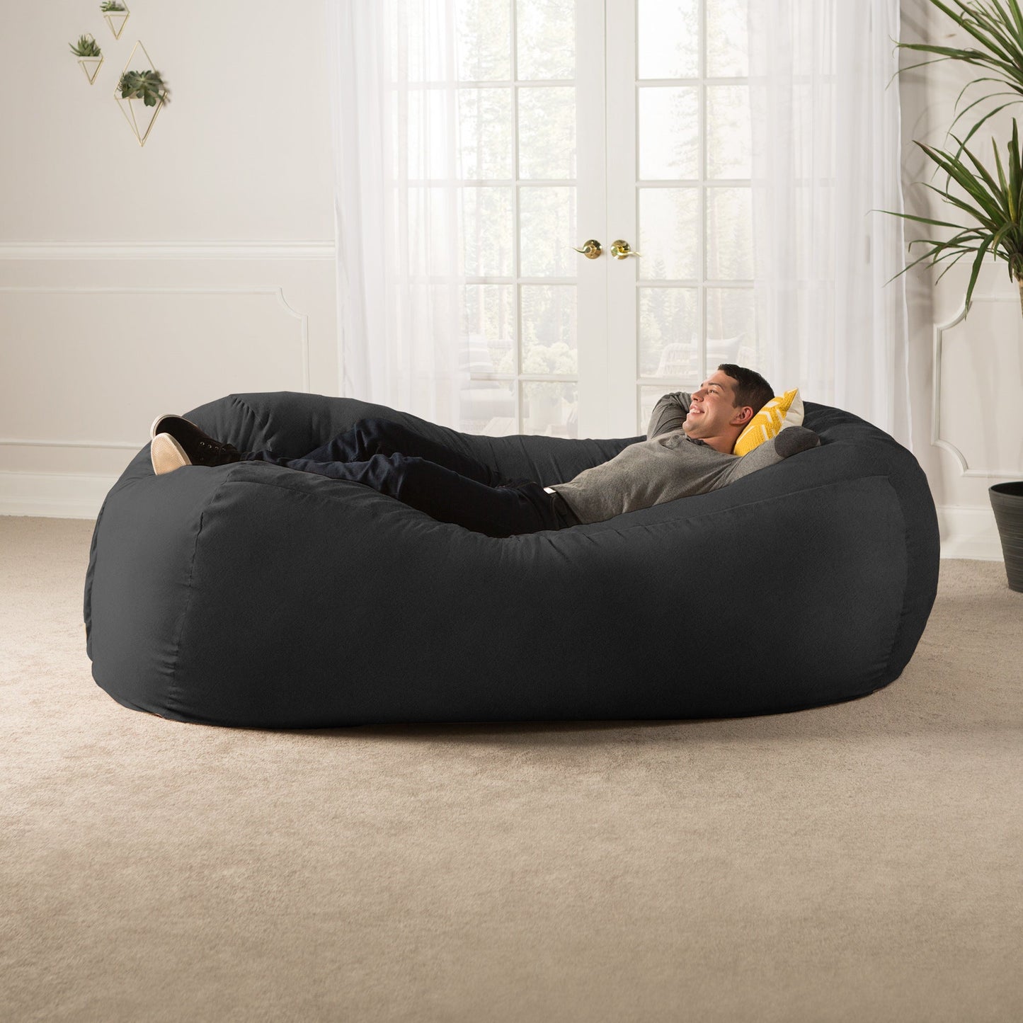 Black giant bean bag sofa with one person reclining, rounded beanbag design