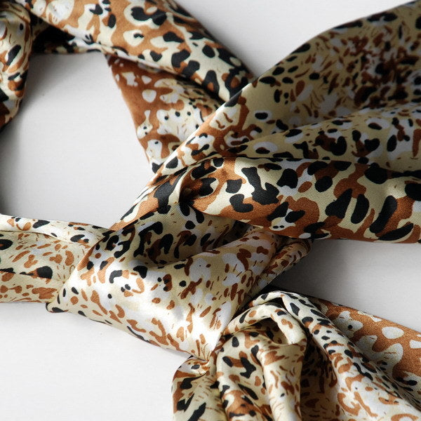 Leopard print silk scarf close-up with knotted folds and gold flecks