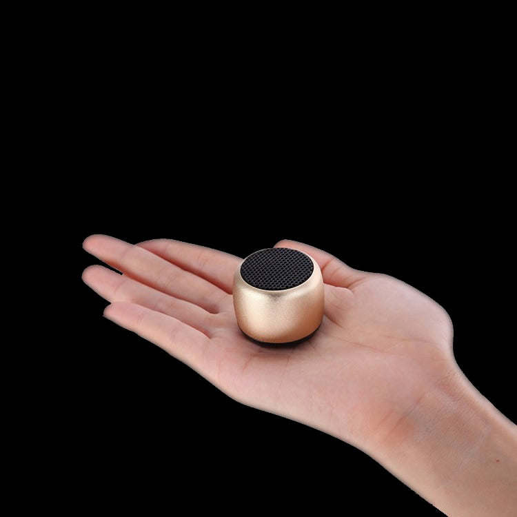 Rose gold mini Bluetooth speaker held in a hand with top speaker grille