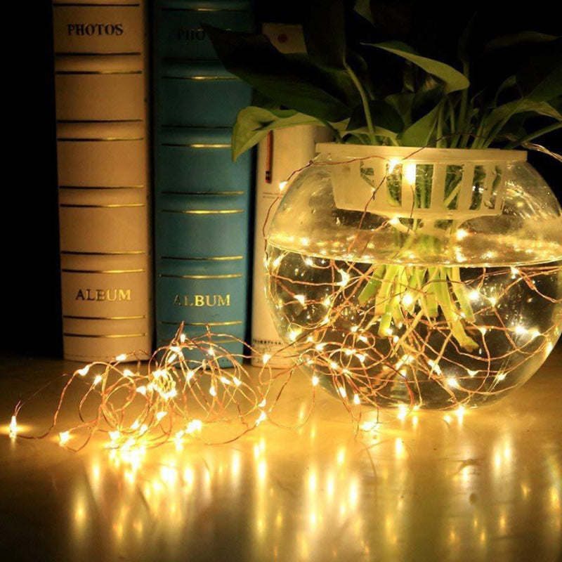 Warm yellow LED string lights wrapped around a glass container with glowing strands