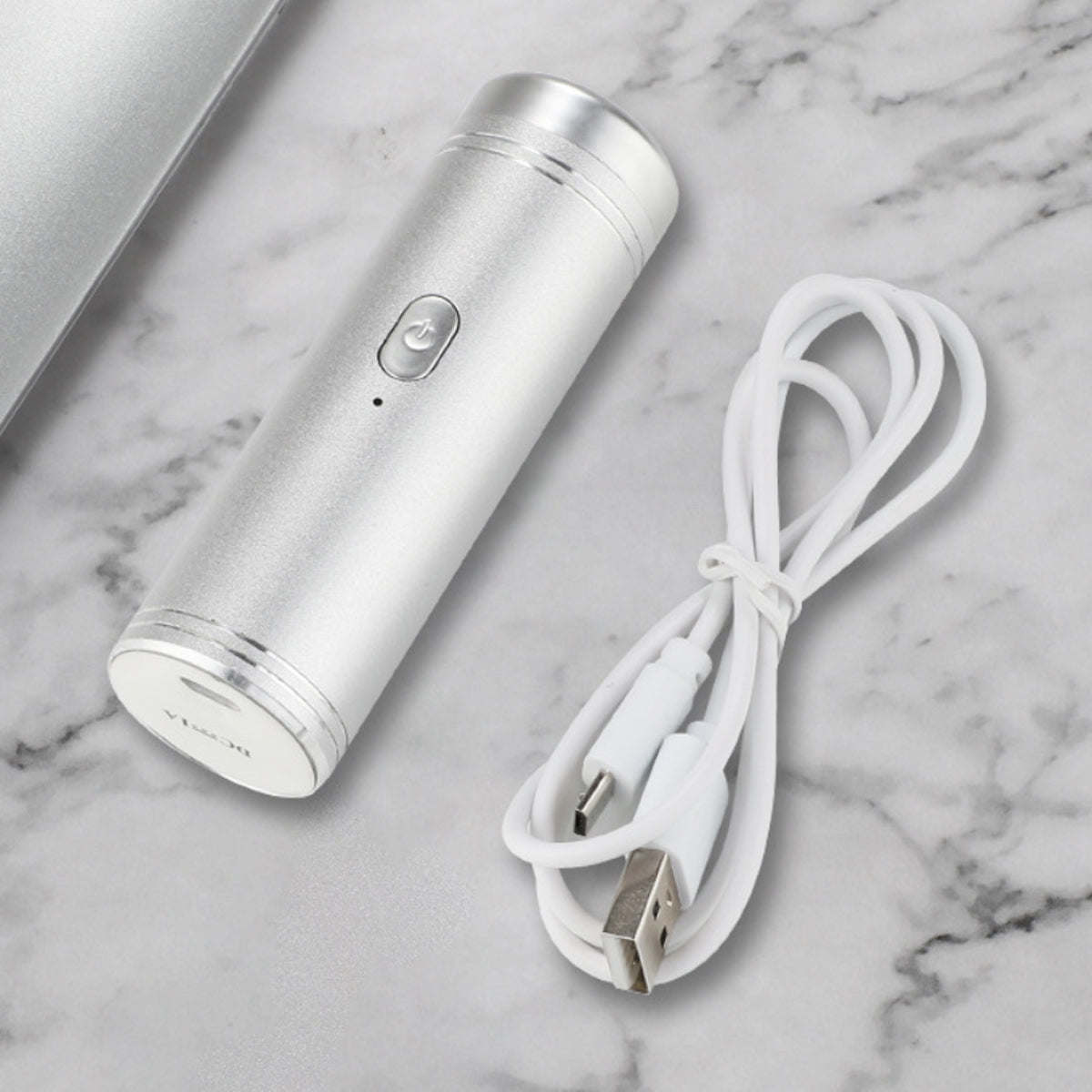Silver mini USB shaver with white charging cable on marble surface