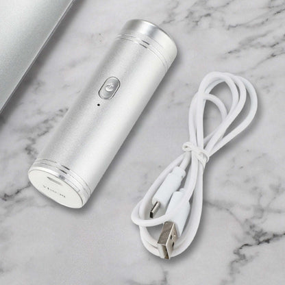 Silver mini USB shaver with white charging cable on marble surface