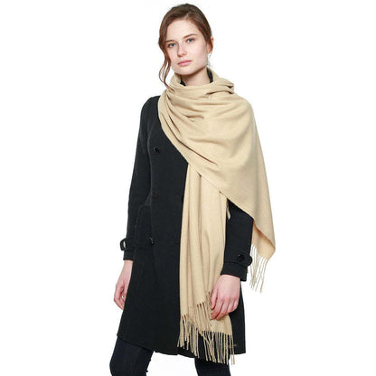 Beige pashmina shawl with long fringe, wrapped and draped across shoulders