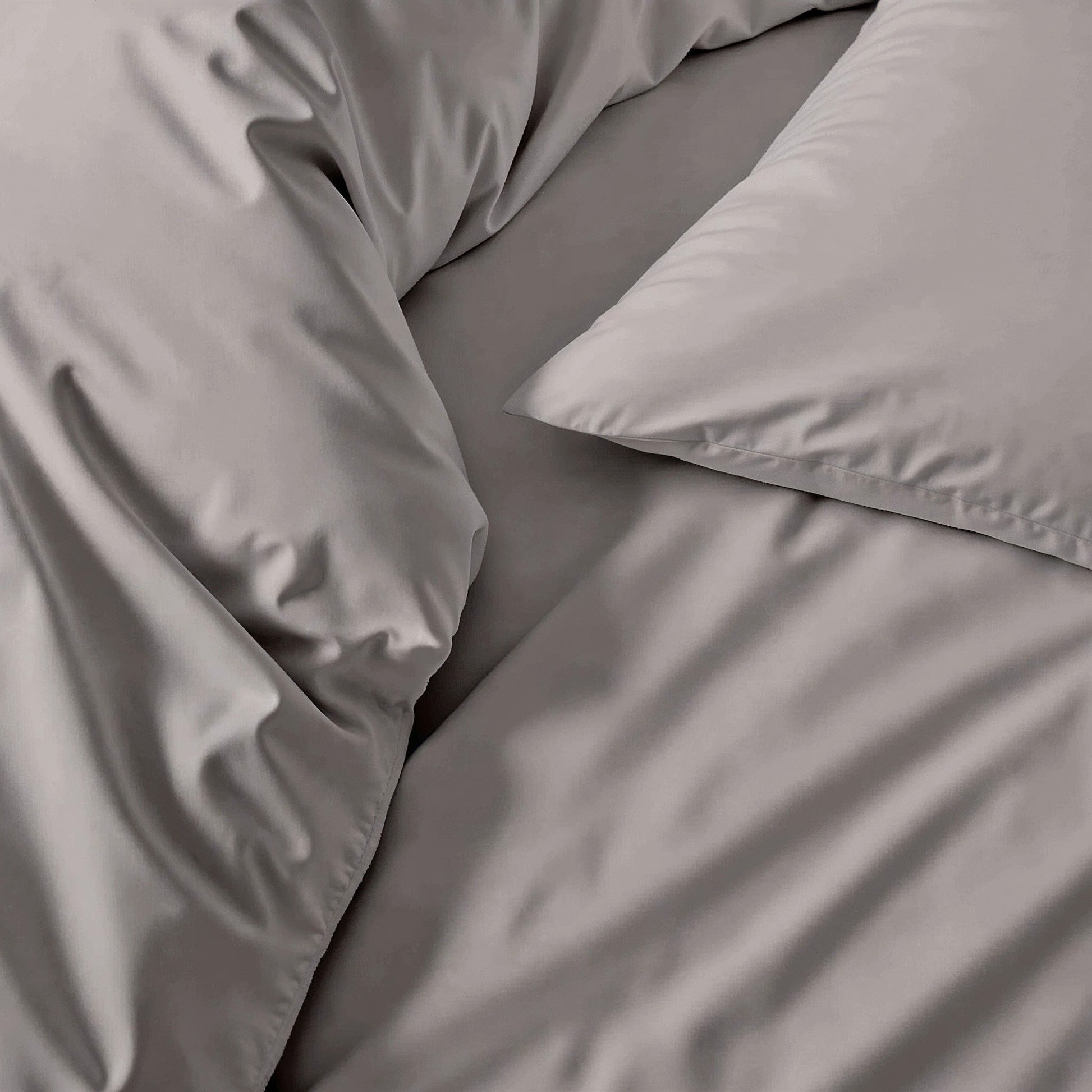 Gray sateen bedding fabric close-up with smooth, wrinkle-textured finish