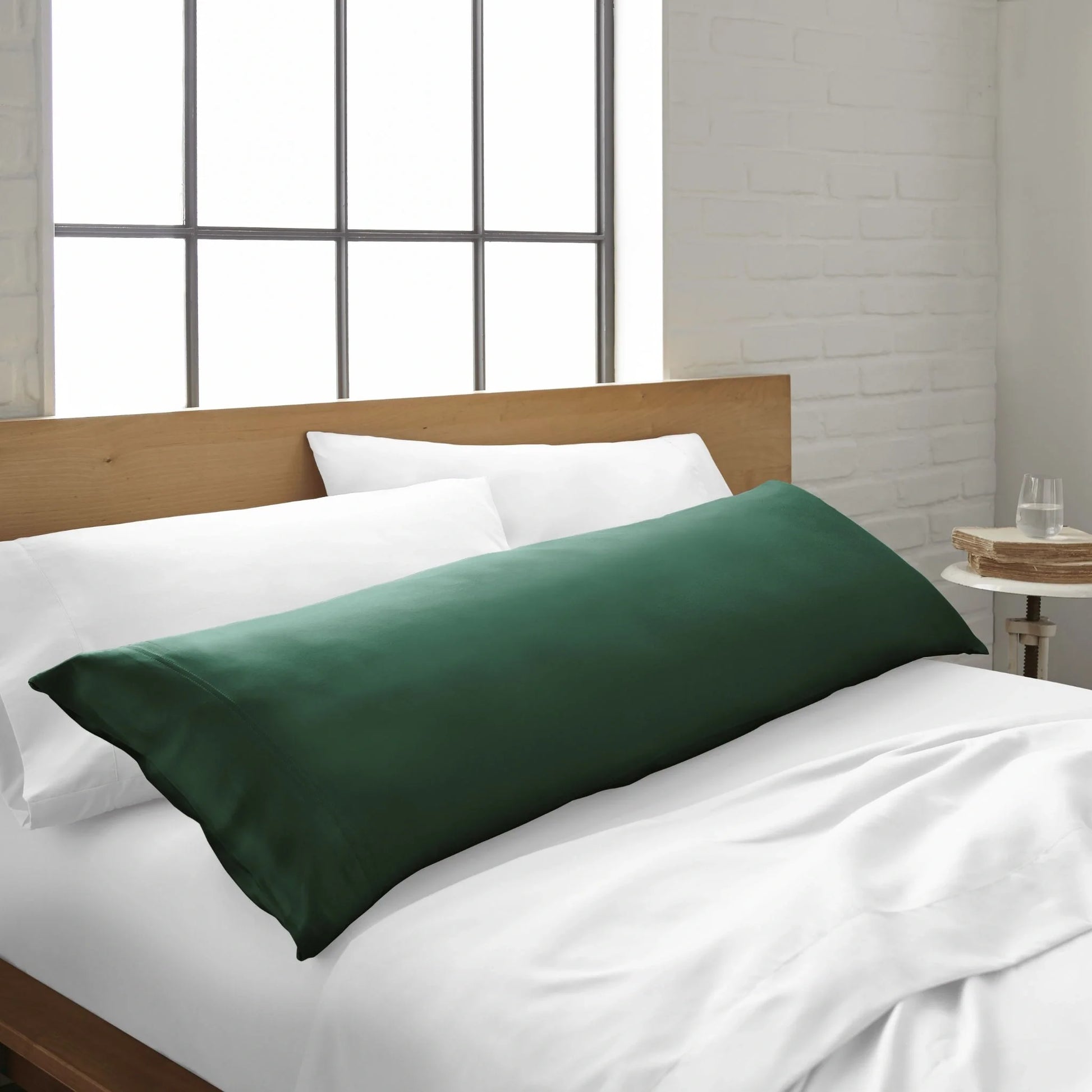 Bamboo body pillowcase in emerald green, on a bed with a white sheet