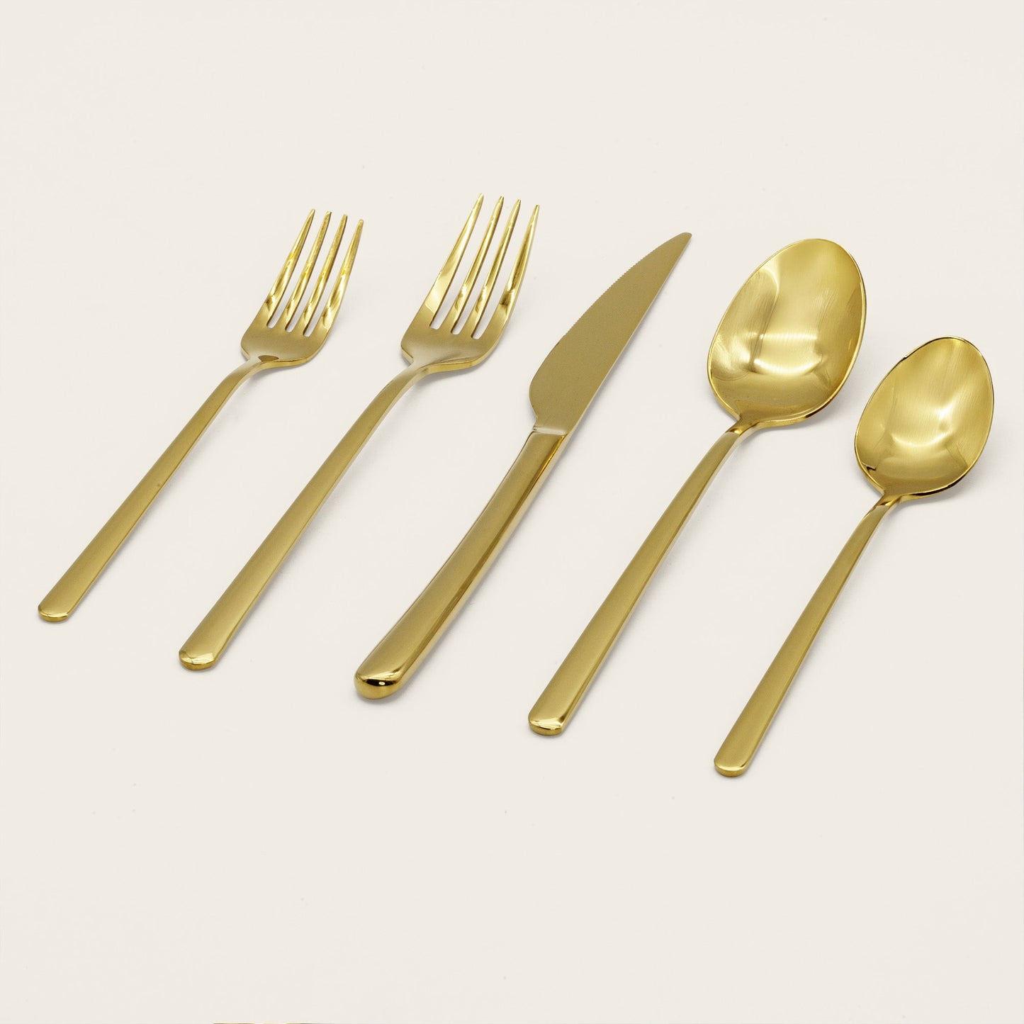 Gold flatware set with two forks, knife, and two spoons displayed
