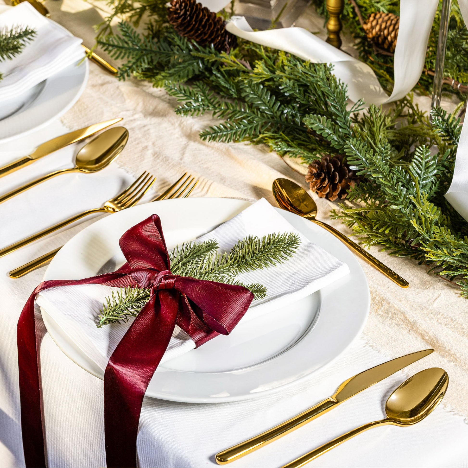 Gold flatware on festive table setting with spoon, fork, and knife by plates