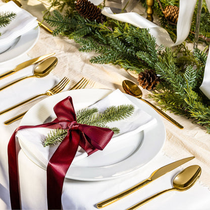Gold flatware on festive table setting with spoon, fork, and knife by plates
