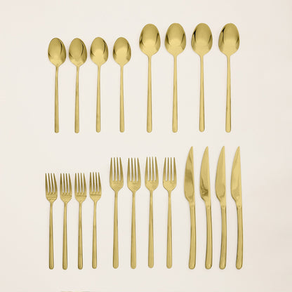 Gold flatware set pieces laid out: spoons, forks, and knives on a light surface