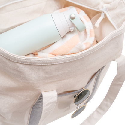 Beige canvas tote interior with zip pouch and sunglasses in front pocket.