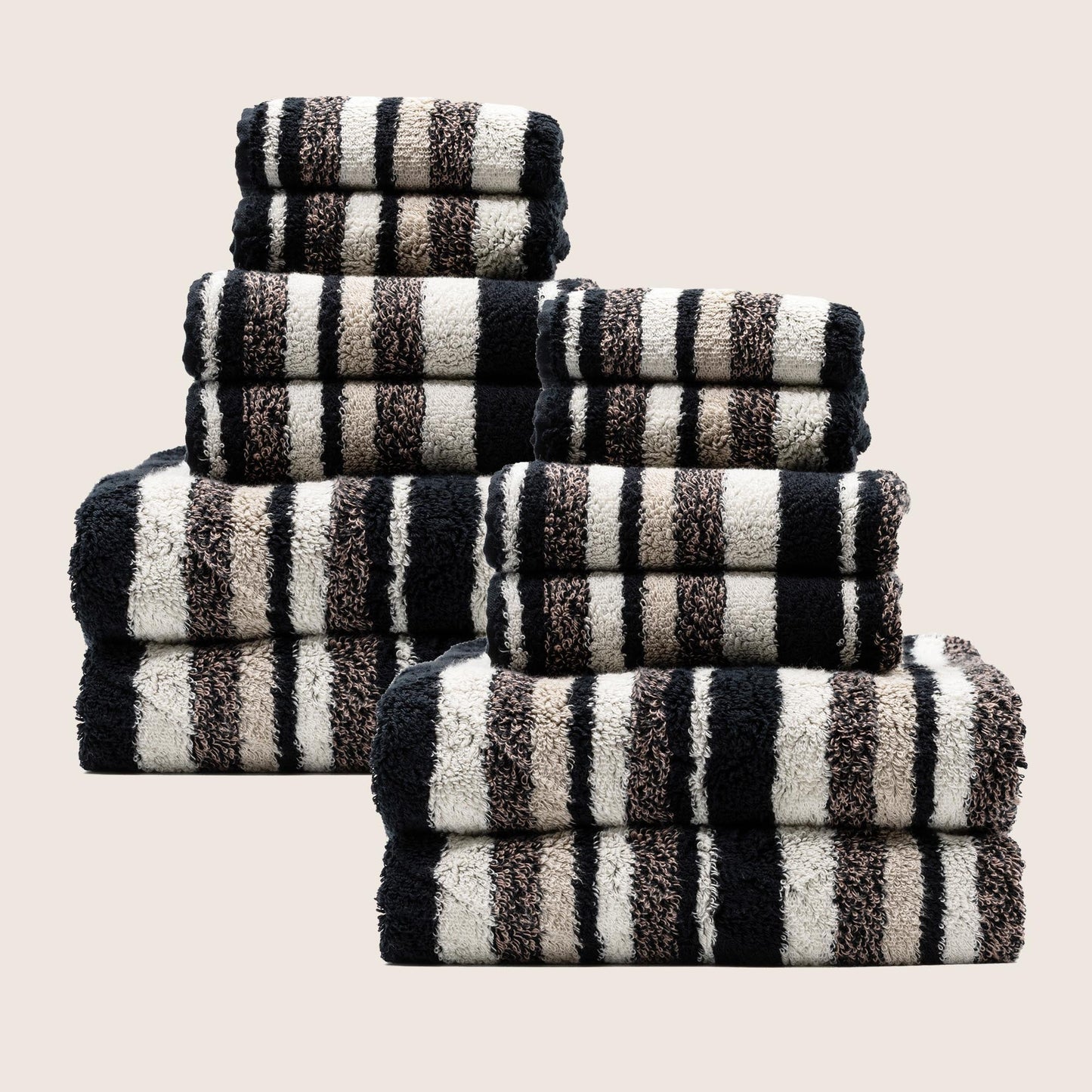 Stack of plush striped towels in dark and light colors, folded with visible check bands.